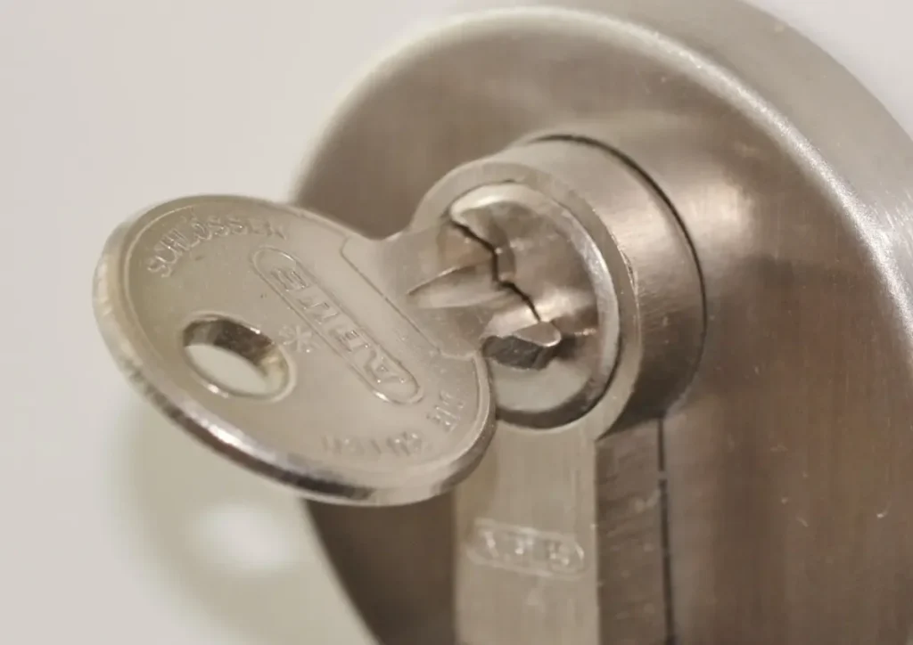 Key inserted in a door lock cylinder – how to choose a trustworthy locksmith in Birmingham before a lock is drilled or replaced, Locksmith Birmingham
