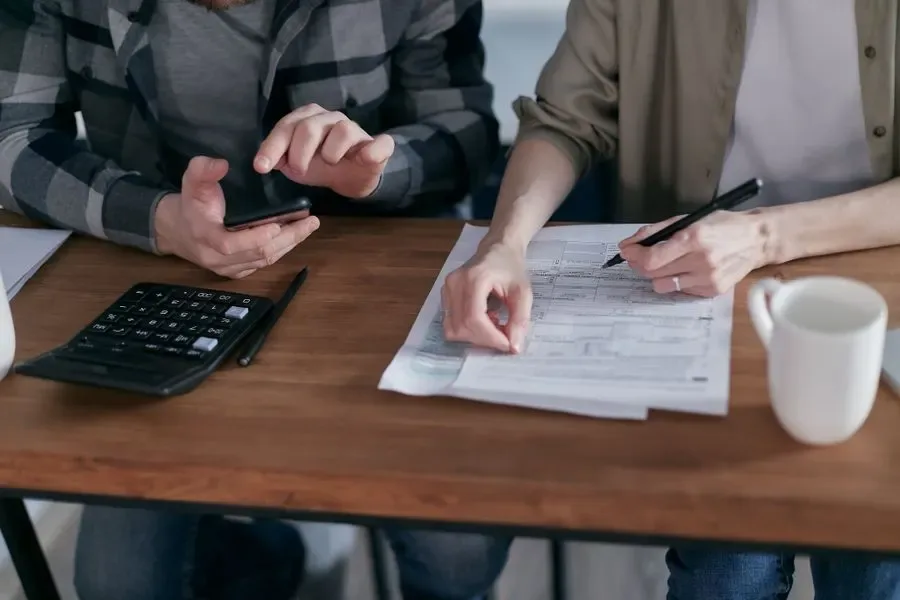 Locksmith prices Birmingham 2026 – customers reviewing a locksmith quote with a calculator, price guide by PDS Locksmiths Birmingham